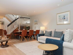 A modern living room with a staircase, dining area, and a sofa with patterned cushions. - Duke's Barn (Totnes)