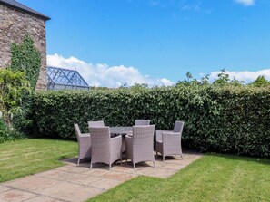 A patio with wicker furniture, a stone wall, and a hedge. - Duke's Barn (Totnes)