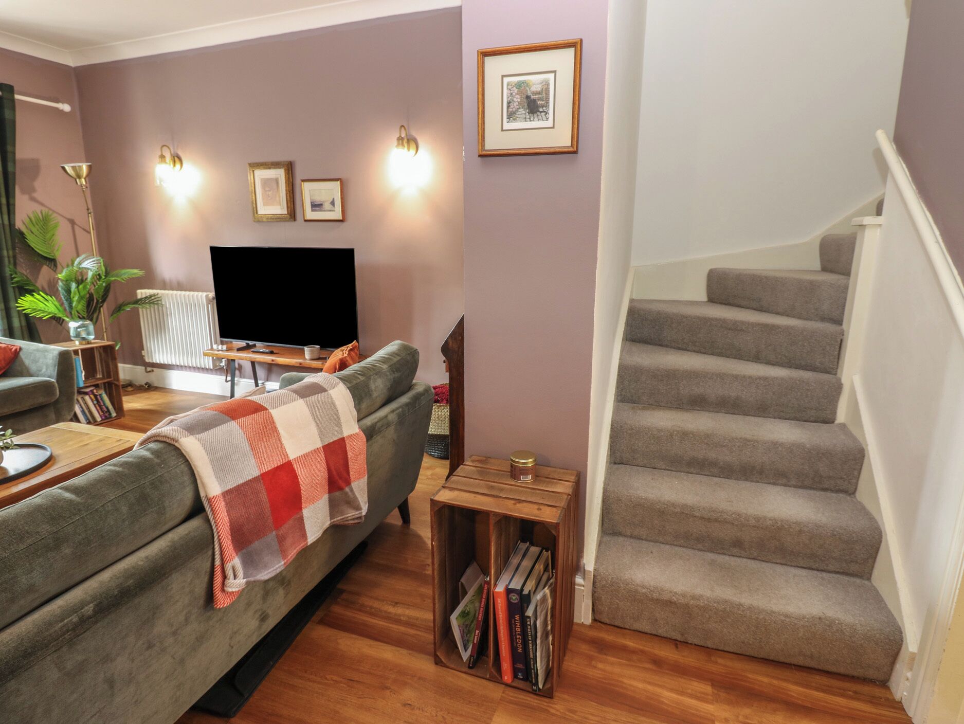 A living room with a sofa, a TV, a bookshelf, and a staircase.