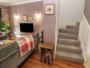 A living room with a sofa, a TV, a bookshelf, and a staircase. - 2 West View (Richmond)