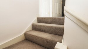 Eine Treppe mit Teppichstufen, die zu einer weißen Tür führt.
