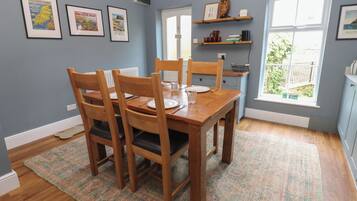 Un comedor con mesa y sillas de madera, cuadros en la pared y una ventana con vistas.