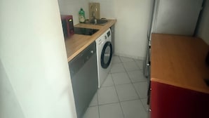 A compact kitchen with a washing machine, a sink, and a refrigerator. - Paradise Riviera St laurent du Var-Nice  (Saint-Laurent-du-Var)
