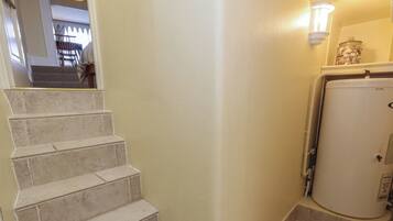 A staircase with beige tiles leading to a landing, a white wall, and a white appliance in the corner.