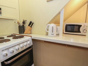 A kitchen with a stove, a kettle, and a microwave. - Number 3 by the Sea (Weymouth)