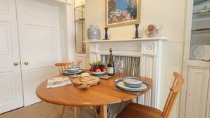 A dining table with chairs, a fireplace, a painting, and a vase. - Number 3 by the Sea (Weymouth)