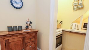 A compact kitchen with a wooden cabinet, a stove, and a microwave. - Number 3 by the Sea (Weymouth)