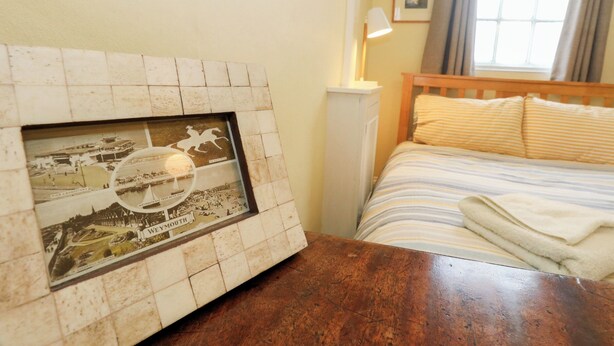 A hotel room with a framed historical photo, a wooden headboard, a bedside lamp, and a window with curtains. - Number 3 by the Sea (Weymouth)