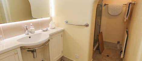 A bathroom with a sink, mirror, towel rack, and shower area.