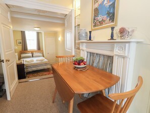 Ein Hotelzimmer mit einem Holztisch, einem Kamin, einem Bett mit gestreifter Bettdecke und einem Bild an der Wand.