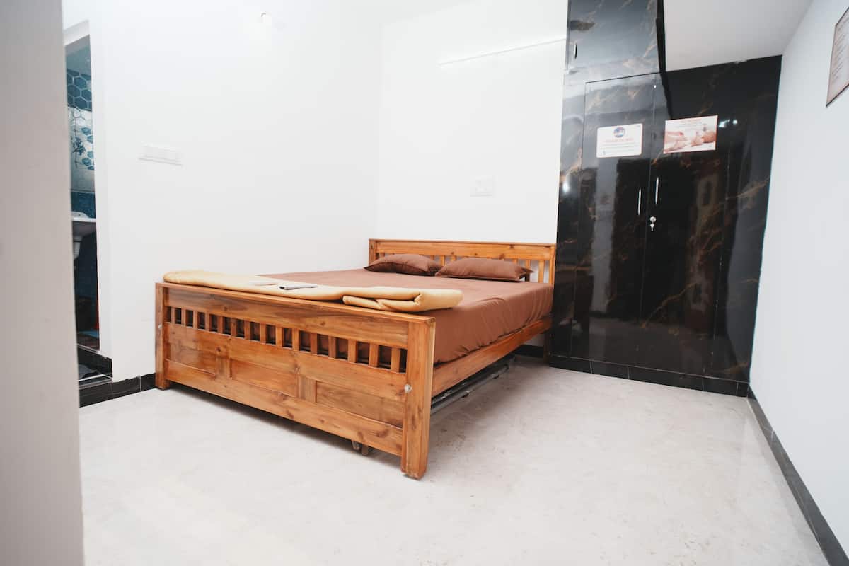 Une chambre à coucher avec un lit en bois, des murs blancs et une porte noire.