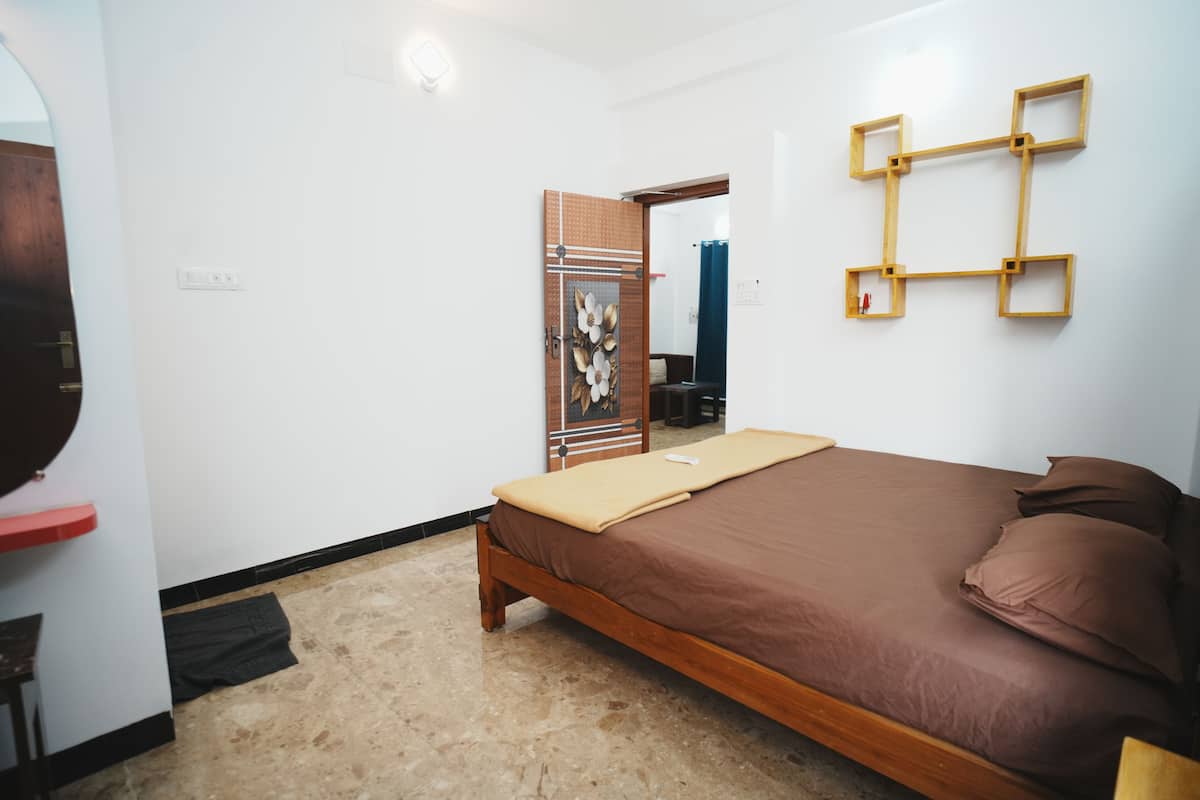 Une chambre avec un lit en bois, une armoire à motifs floraux et une étagère fixée au mur.