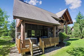 Eine Lodge mit überdachter Veranda, Whirlpool und Kamin aus Stein.
