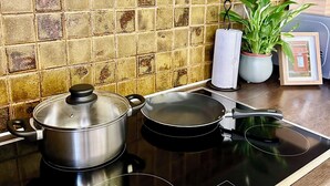 A kitchen with a stove, pots, a potted plant, and a framed picture on the counter.