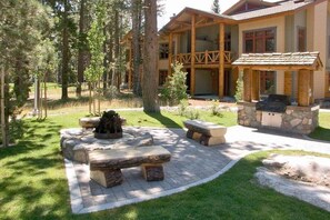 A lodge with a stone fire pit, outdoor seating, and a stone grill area. - Golf Course Property, Allows Pets, BBQ, Underground Parking, Laundry (Mammoth Lakes)