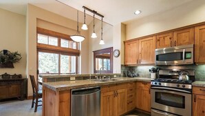 Une cuisine dotée de meubles en bois, d’appareils électroménagers en acier inoxydable et d’un grand îlot central avec un lave-vaisselle.