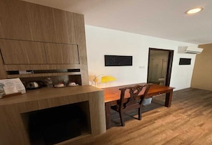 A compact kitchen with wooden cabinets, a dining table with chairs, and a small yellow lamp. - Palette - Bukit Mata Boutique Hotel (Kuching)