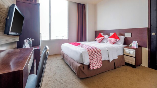 Quarto de hotel com cama, mesa de cabeceira e televisão na parede.