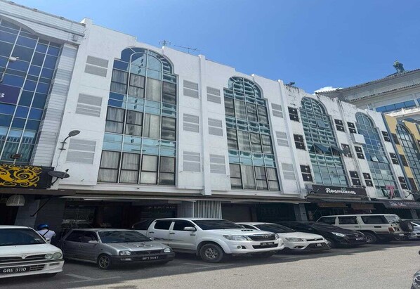 Un edificio de varios pisos con grandes ventanales y un estacionamiento frente a él.