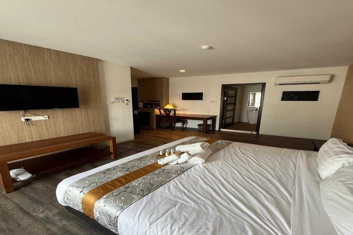 Habitación de hotel con cama, mesita de noche, televisión y escritorio con silla.