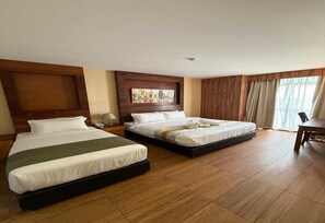 A hotel room with two beds, a wooden headboard, a painting above the beds, and a large window with curtains. - Palette - Bukit Mata Boutique Hotel (Kuching)