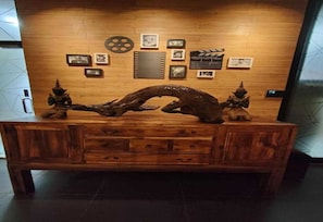 A wooden reception desk with a large, curved sculpture in the center, flanked by two smaller sculptures. - Palette - Bukit Mata Boutique Hotel (Kuching)
