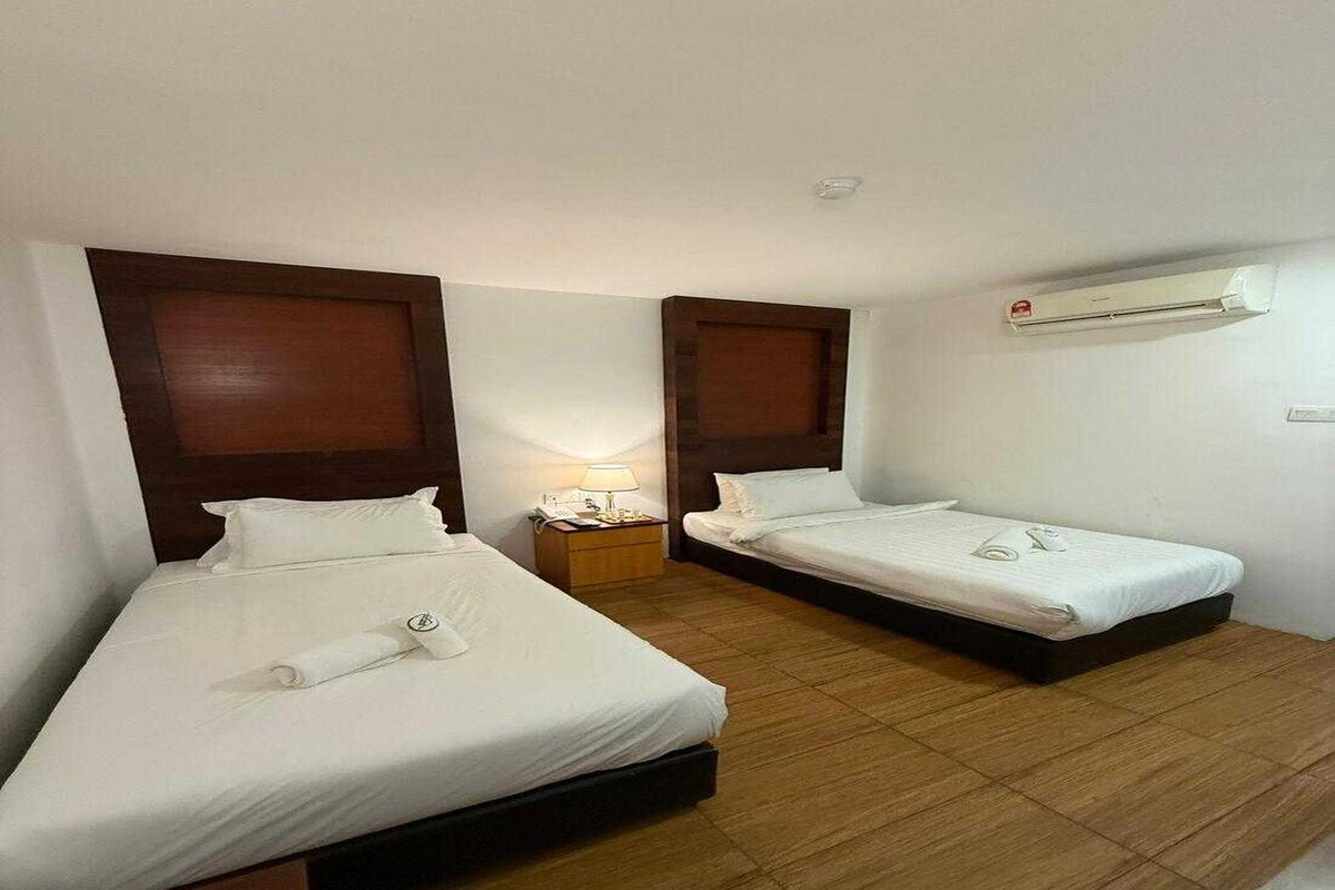 Una habitación de hotel con dos camas, una mesita de noche, una lámpara y un equipo de aire acondicionado.