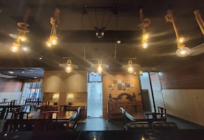 A restaurant interior with hanging light fixtures, wooden tables, and chairs. - Palette - Bukit Mata Boutique Hotel (Kuching)
