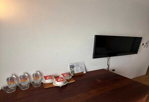 Ein Holztisch mit einem an der Wand befestigten Flachbildfernseher, einer Zeitung und einem Tablett mit Tassen und Gewürzen.