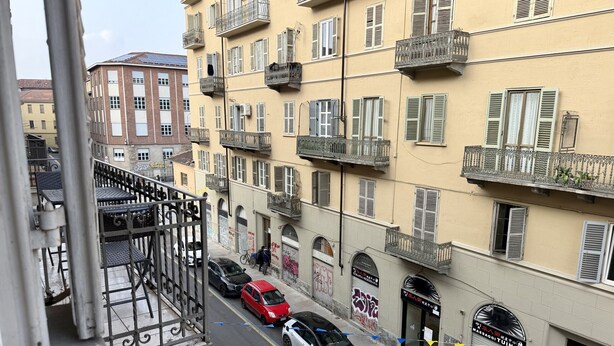 Une vue de rue avec des voitures garées, un immeuble doté de balcons et une enseigne indiquant « Massaggitina ».