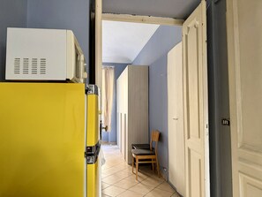 A hallway with a yellow appliance, a wooden chair, and a door leading to another room. - Purple Nest House (Turin)