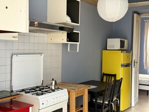 A kitchen with a gas stove, a microwave, a yellow refrigerator, and a dining table with chairs. - Purple Nest House (Turin)