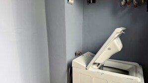 Une pièce avec un radiateur blanc, un thermostat fixé au mur et une prise électrique visible.