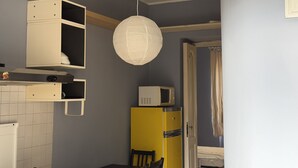 Une cuisine de taille réduite, équipée d’un four à micro-ondes, d’un réfrigérateur jaune et d’une lanterne en papier suspendue.