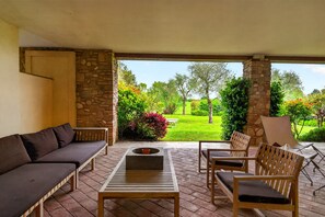 Un patio exterior con un sofá, sillas y una mesa.