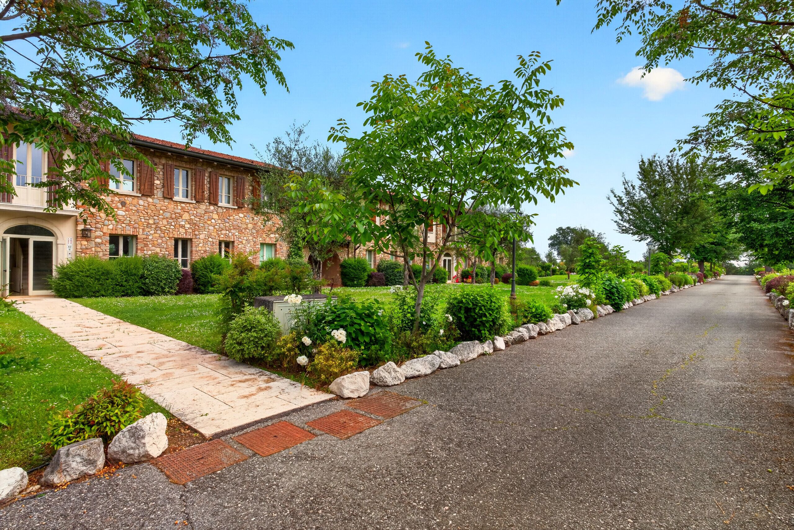 A stone building with a paved driveway and well-maintained landscaping.