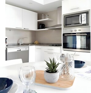 Een moderne keuken met witte kastjes, een ingebouwde oven en een magnetron.
