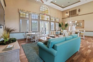 A spacious living area with a large sofa, dining table, and chairs, large windows with curtains, and a ceiling fan. - Direct Intracoastal Waterway condo in Canopy Walk #745! (Palm Coast)