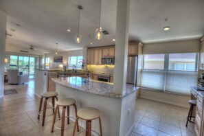 A spacious kitchen with a central island, bar stools, and modern appliances. - Direct Intracoastal Waterway condo in Canopy Walk #745! (Palm Coast)