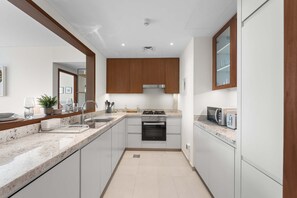 Eine moderne Küche mit weißen Schränken, einer Granit Arbeitsplatte, einem Einbauofen und einer Mikrowelle.