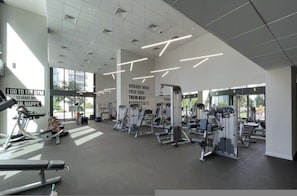 Ein Fitnessstudio mit Trainingsgeräten, motivierenden Postern und großen Fenstern.