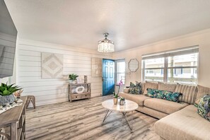 A living room with a sofa, coffee table, and decorative items. - Gulf Shores Beach Condo With Pool (Gulf Shores)