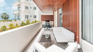 Un balcon doté d’un plafond en bois, de meubles blancs et offrant une vue sur un immeuble également pourvu de balcons.