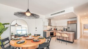 Une cuisine moderne avec un îlot central, des meubles blancs et une grande fenêtre.