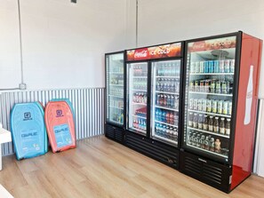 A Coca-Cola refrigerator stocked with various beverages, two QWAVE branded bags, and a white table. - Waterfront 2-bedroom Condo in Panama City (Panama City)