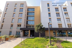 Ein mehrstöckiges Gebäude mit einer glatten Fassade, großen Fenstern und einem kleinen Baum im Vordergrund.