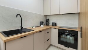 Eine moderne Küche mit einem schwarzen Spülbecken, einer Kaffeemaschine und einem eingebauten Backofen.