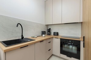 Eine moderne Küche mit einem schwarzen Spülbecken, einer Kaffeemaschine und einem eingebauten Backofen.