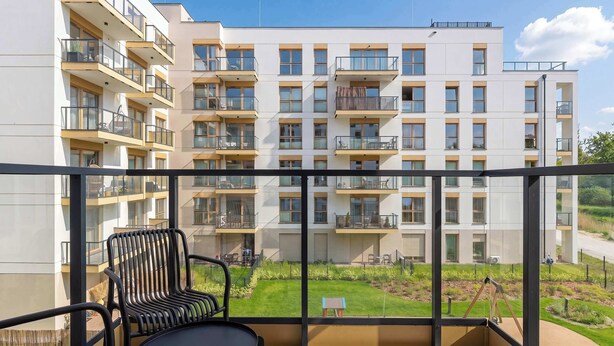 Ein Balkon mit Blick auf ein mehrstöckiges Gebäude, einem kleinen Tisch und einem Stuhl.