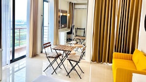 A modern living room with a dining area, large windows, and a yellow sofa. - Vrindavan Staycation (Mathura)